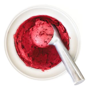 Featured photo for Damson Plum Sorbet recipe: shows a scoop in an, ice cream maker bowl filled with freshly churned Damson plum sorbet